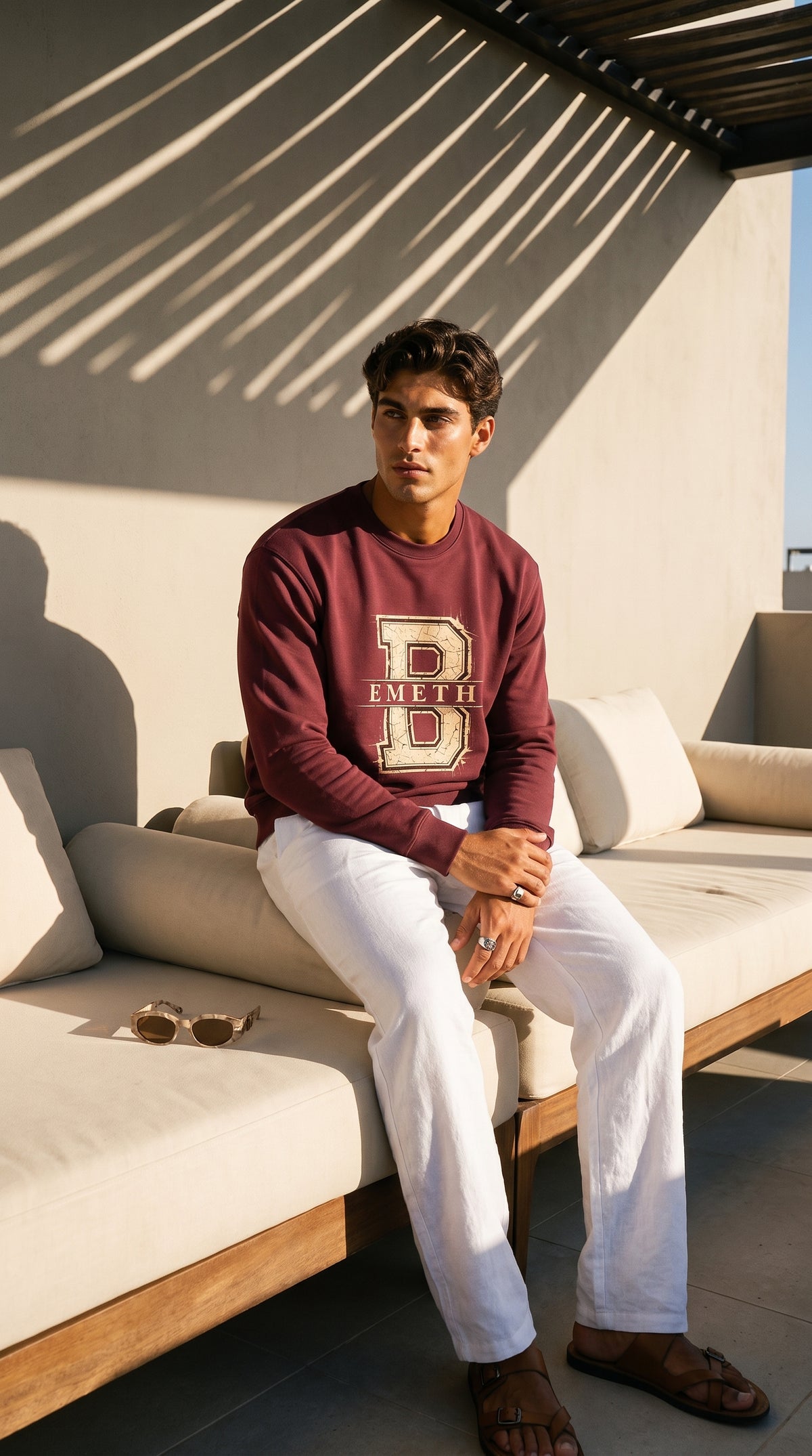 Sweat col rond EMETH Classic Varsity B rouge foncé porté, assis sur une terrasse