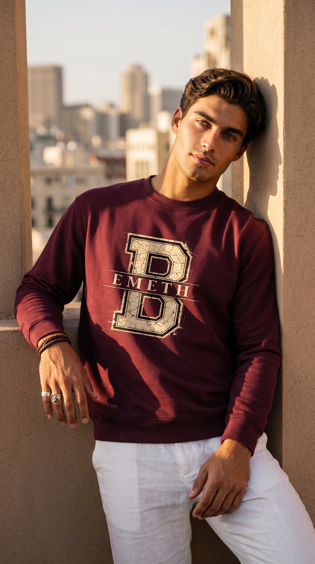 Sweat col rond EMETH Classic Varsity B rouge foncé porté, adossé à un mur